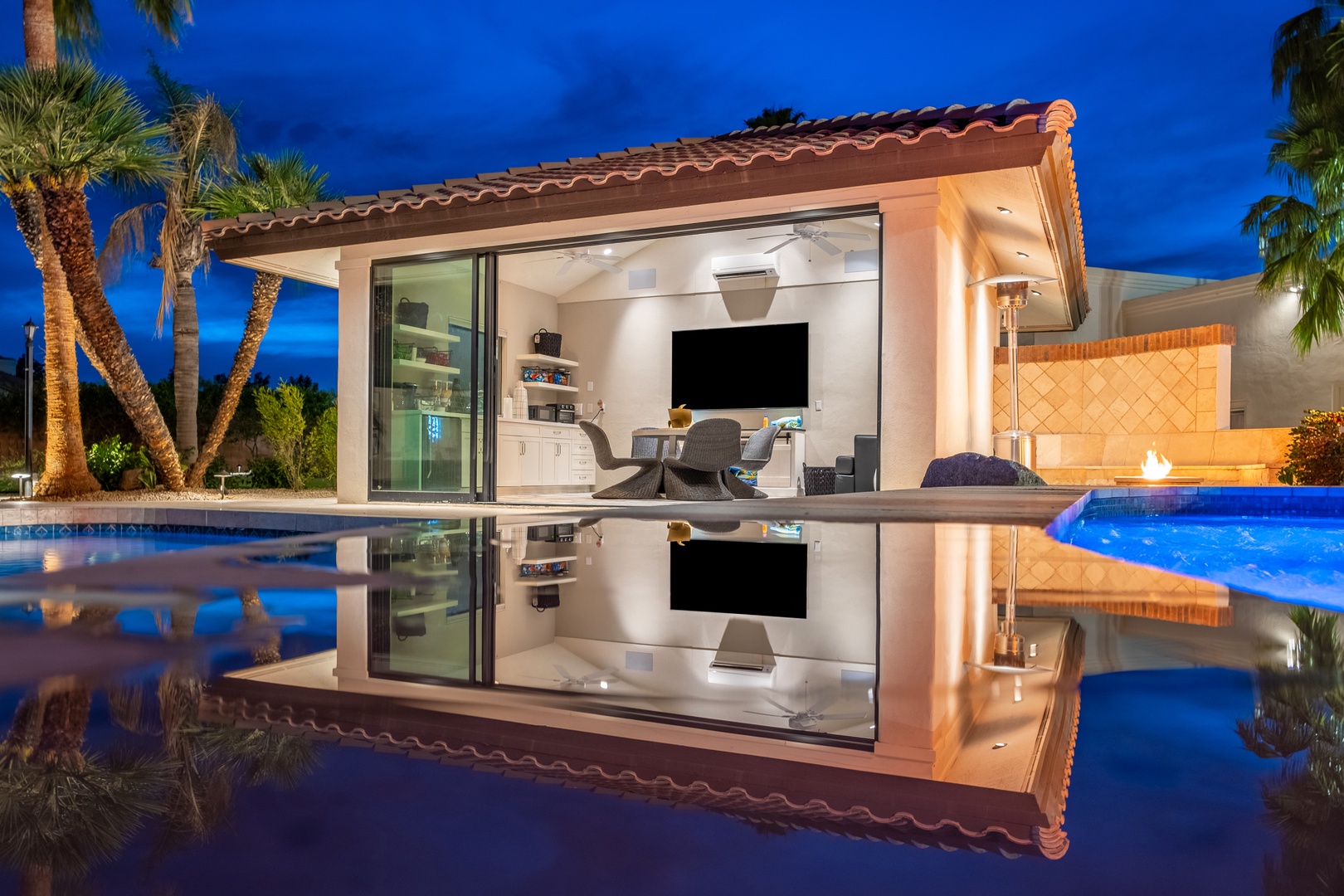 A stunning poolside oasis reflecting the elegant living space at twilight, where modern comfort meets tropical charm beneath swaying palms.