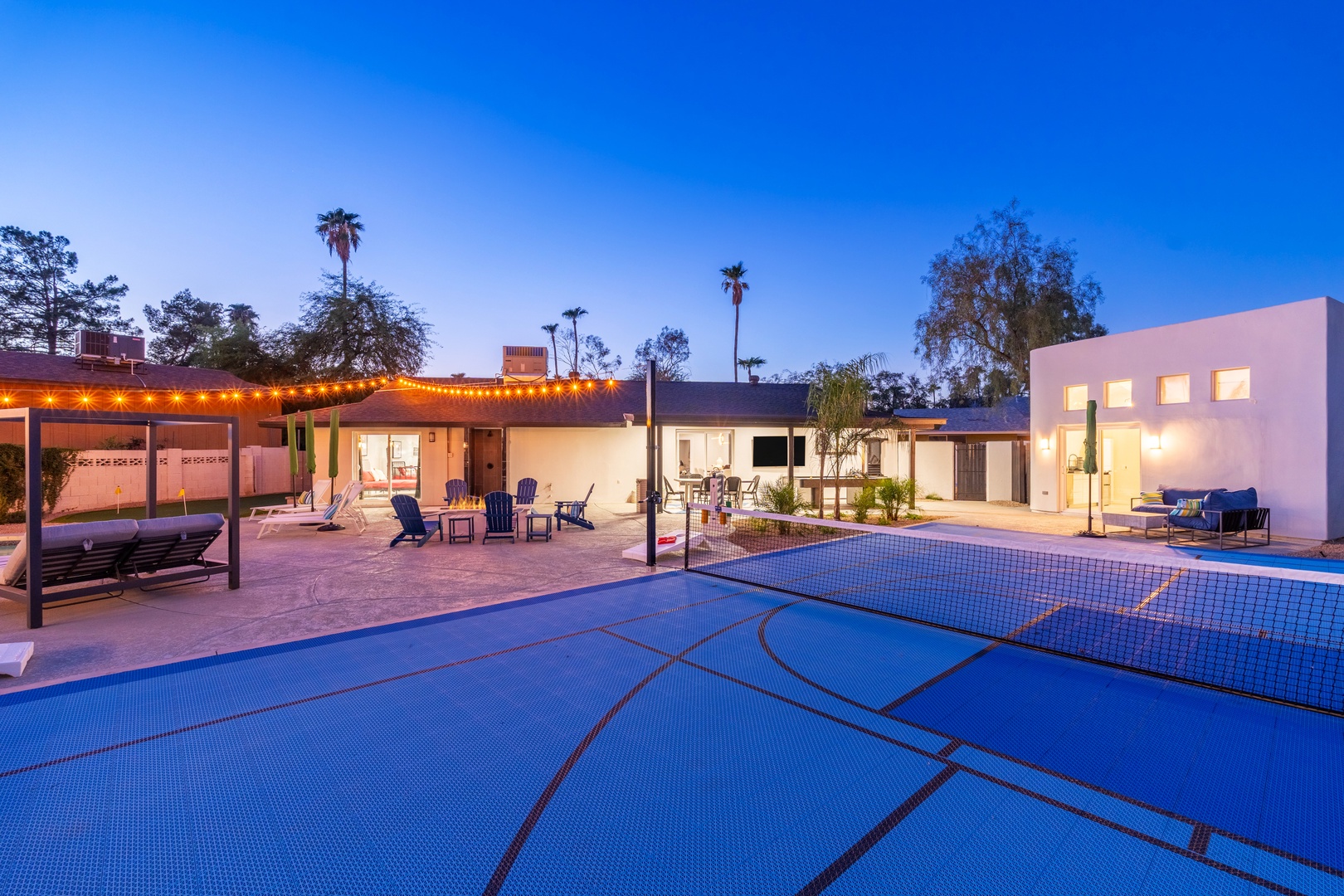 A spacious resort-style property featuring a covered pool, illuminated courtyard seating, and palm trees under a clear evening sky—perfect for groups seeking relaxation and entertainment.