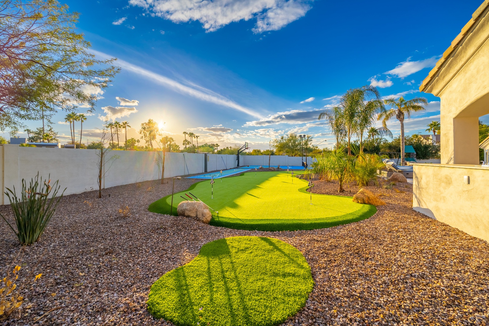 Backyard oasis featuring a private putting green under vibrant desert skies, perfect for practicing your golf swing or simply enjoying warm, sunny days outdoors.