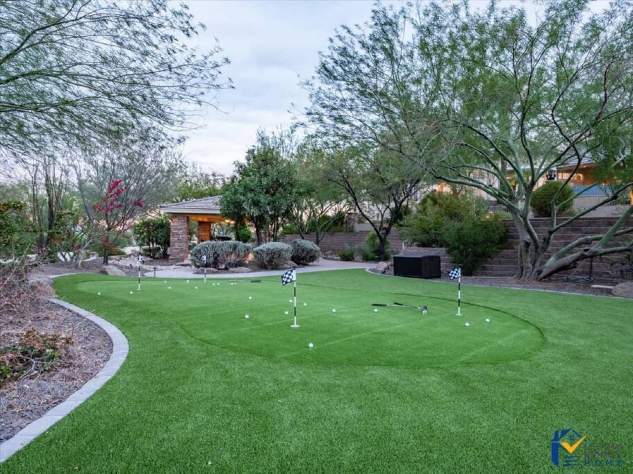 Practice your putting on your private miniature golf course, nestled in a beautifully landscaped backyard with lush greenery and desert charm.