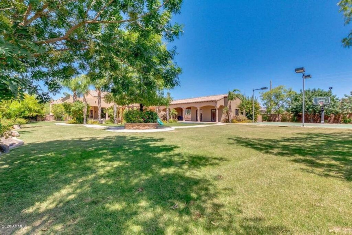 Expansive property grounds feature manicured lawns, mature trees, and recreational amenities including a basketball court.
