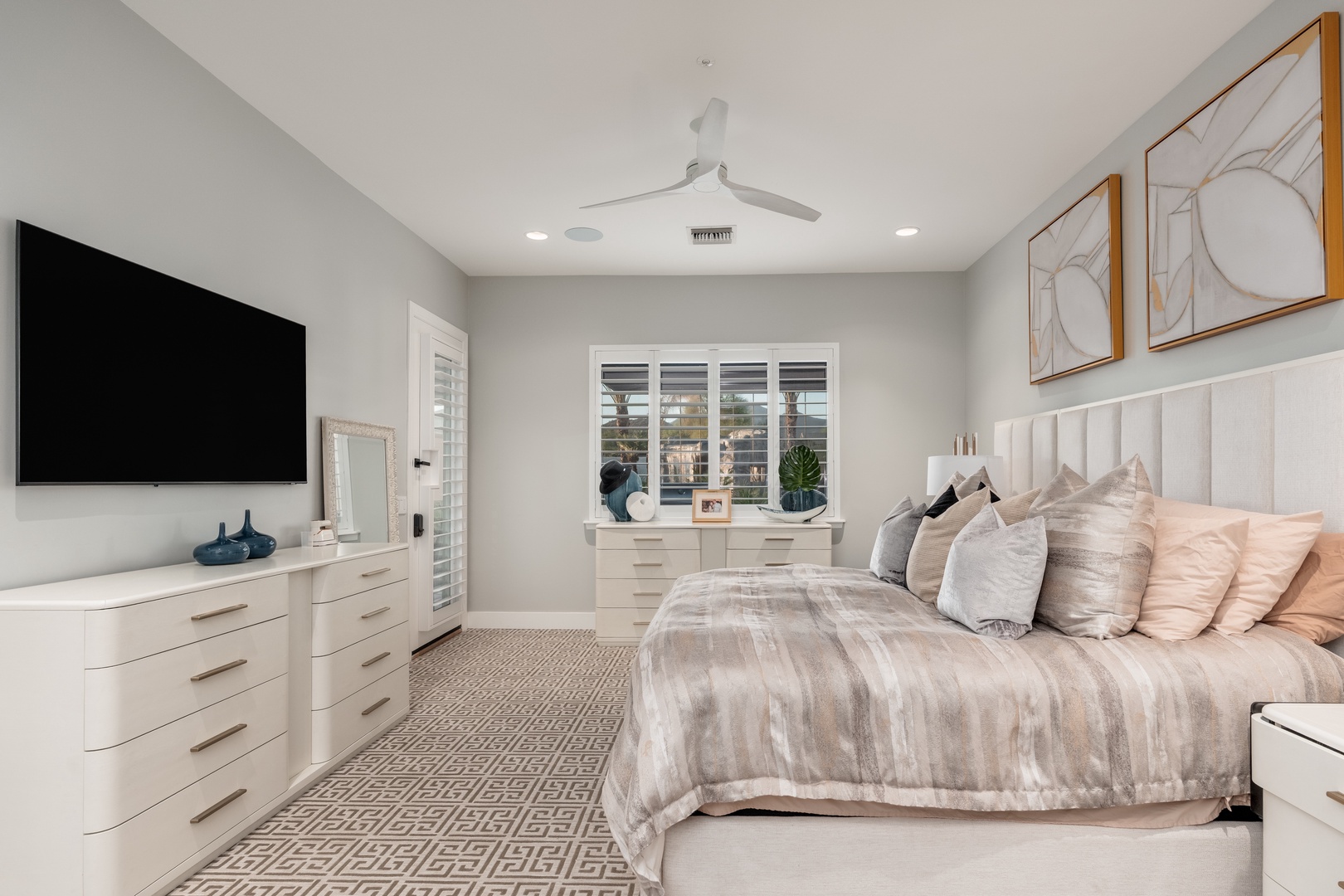 You'll unwind in this serene bedroom with a plush bed, calming neutral tones, and elegant décor. Ceiling fans keep you comfortable while natural light fills the space through stylish shutters.