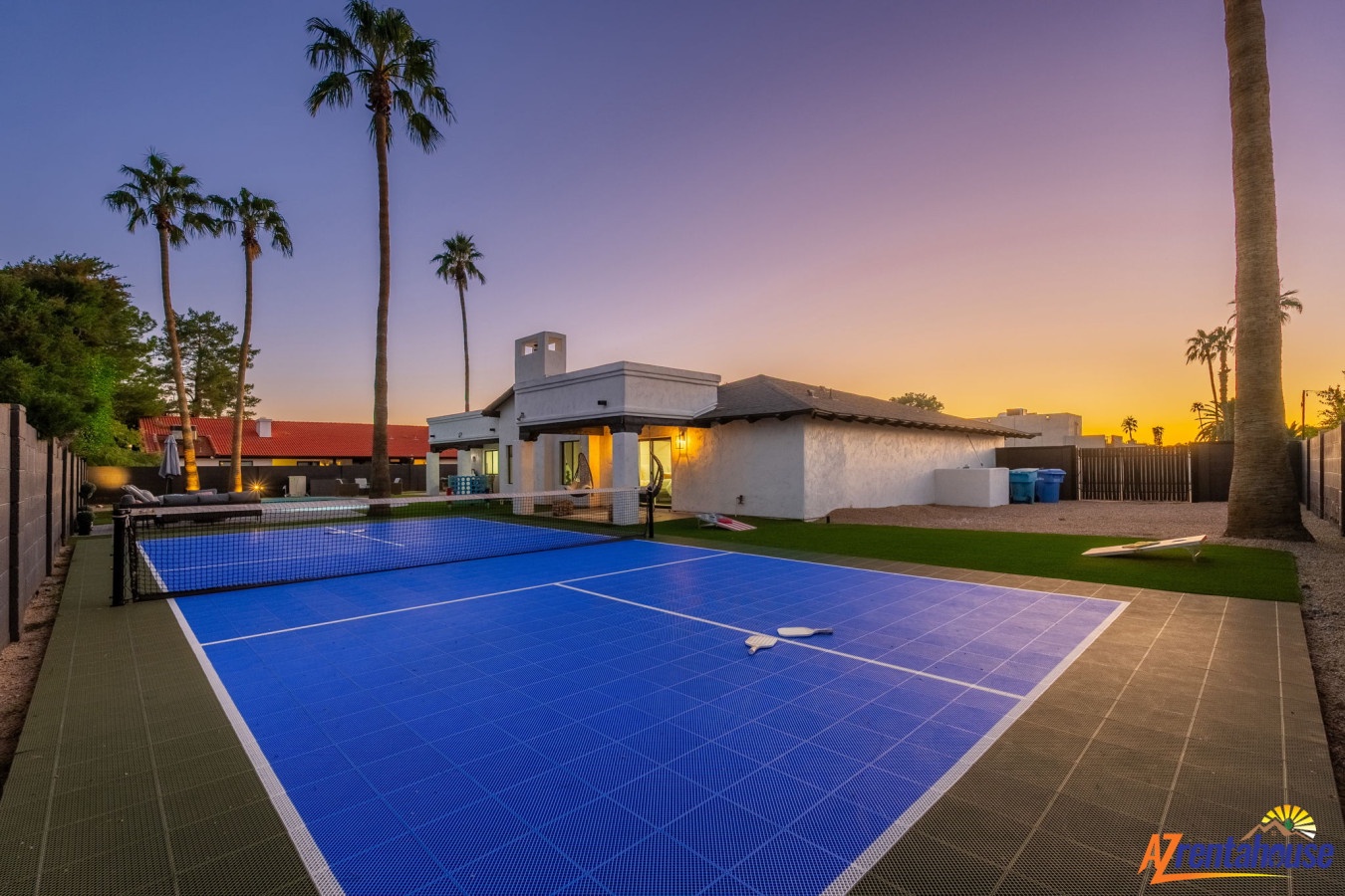 Desert retreat featuring tennis court beneath towering palms and stunning sunset skies.