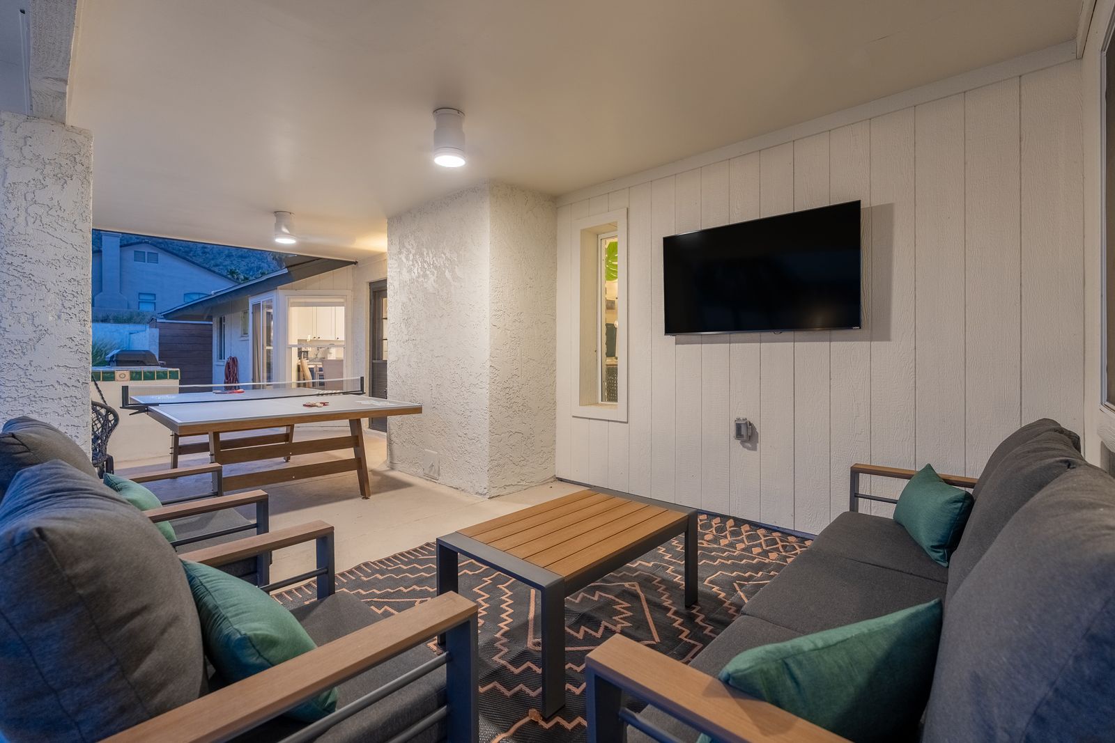 Unwind in your private outdoor lounge, where plush seating and a mounted TV create the perfect spot for evening relaxation under soft lighting.