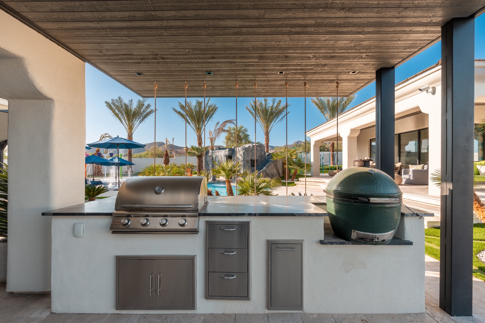 Your private outdoor kitchen features a professional-grade grill and smoker under a stylish covered pavilion, perfect for culinary adventures while taking in the stunning desert and pool views.