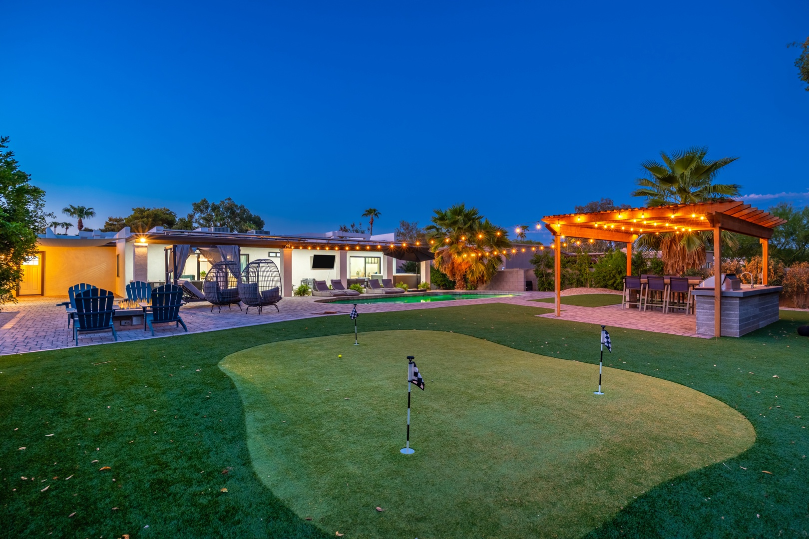 Private putting green, cozy fire pit, and a glowing pergola create the perfect backyard oasis. Your desert escape is framed by palm trees and endless blue skies.