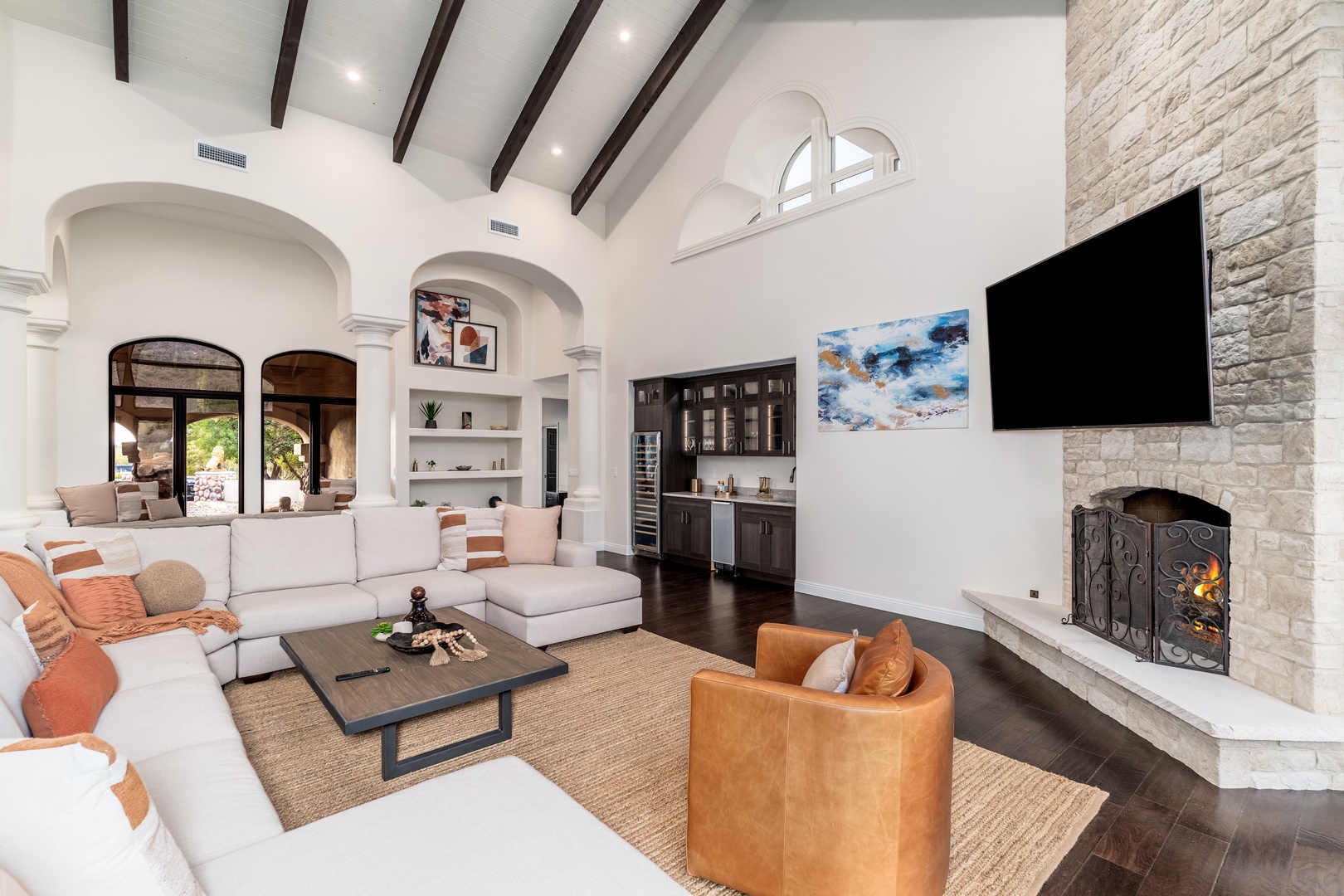 Unwind in this bright, open living area where soaring vaulted ceilings, plush seating, and a cozy stone fireplace create your perfect haven for relaxing evenings together.