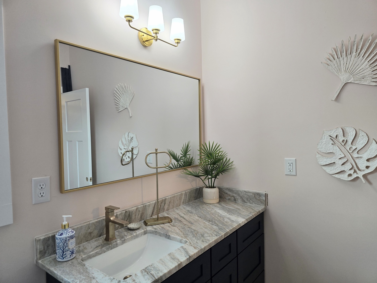 Refresh in your elegant bathroom with marble counters, brass fixtures, and tropical touches creating a spa-like retreat.
