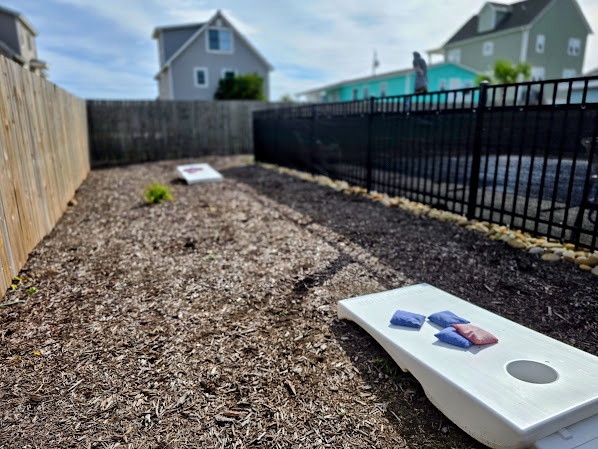 Cornhole court awaits in the fenced backyard.