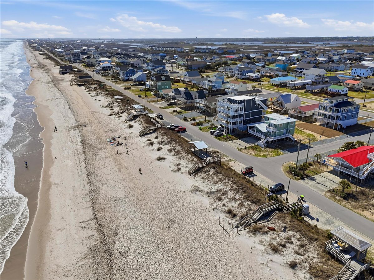 Aerial view showcasing a vibrant beachfront community with colorful vacation homes lining the pristine sandy shore.
