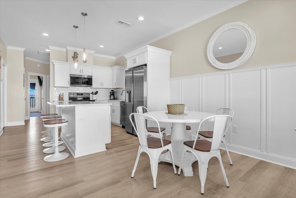 Your bright open kitchen and dining space features white cabinetry, stainless appliances, and stylish seating perfect for morning coffee or evening meals.