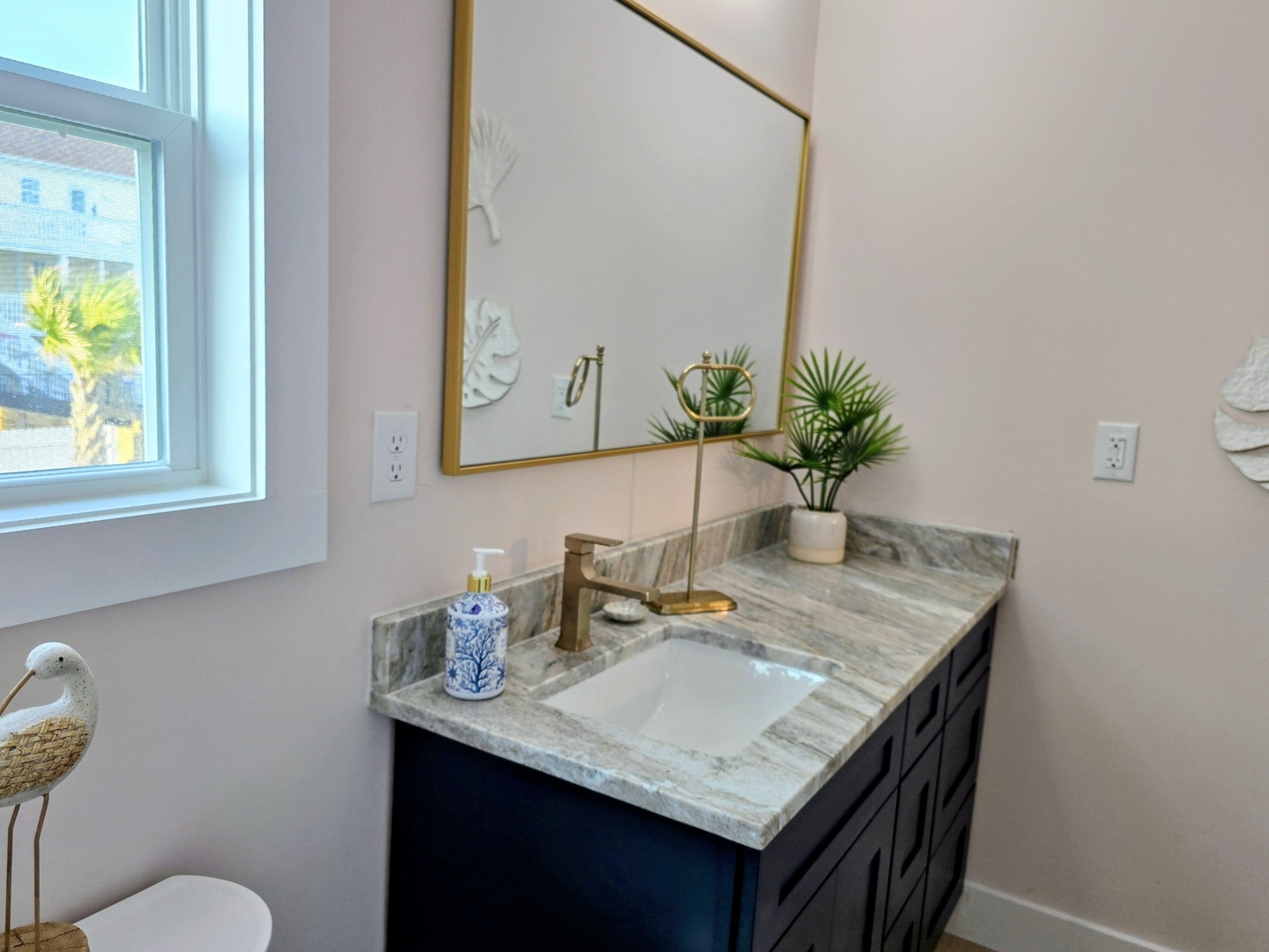 Refresh in your stylish bathroom with marble countertops, gold fixtures, and natural light streaming in.