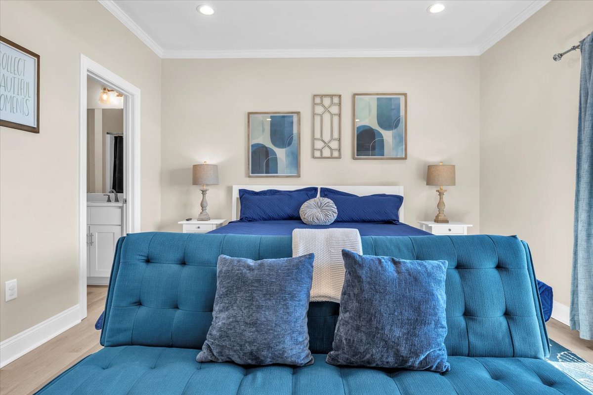 Sink into your stylish bedroom sanctuary with soothing blue tones, plush seating, and coastal artwork creating the perfect retreat.