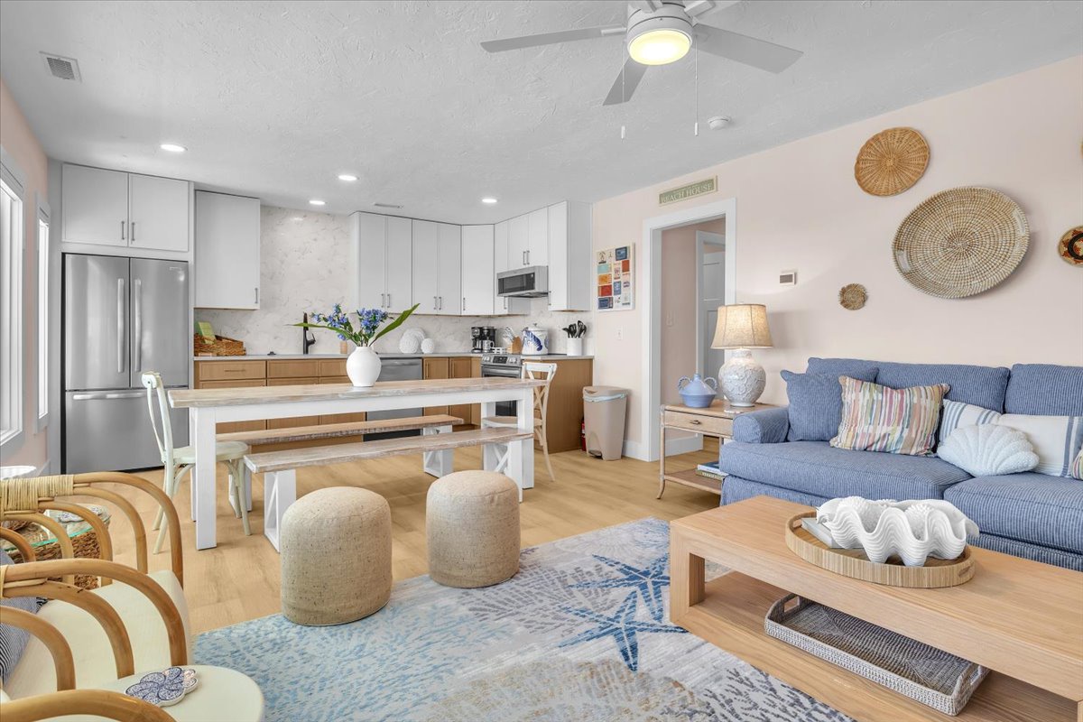 Your open-concept living space combines coastal charm with modern comfort. Relax on the blue sofa or gather around the island for memorable meals together.