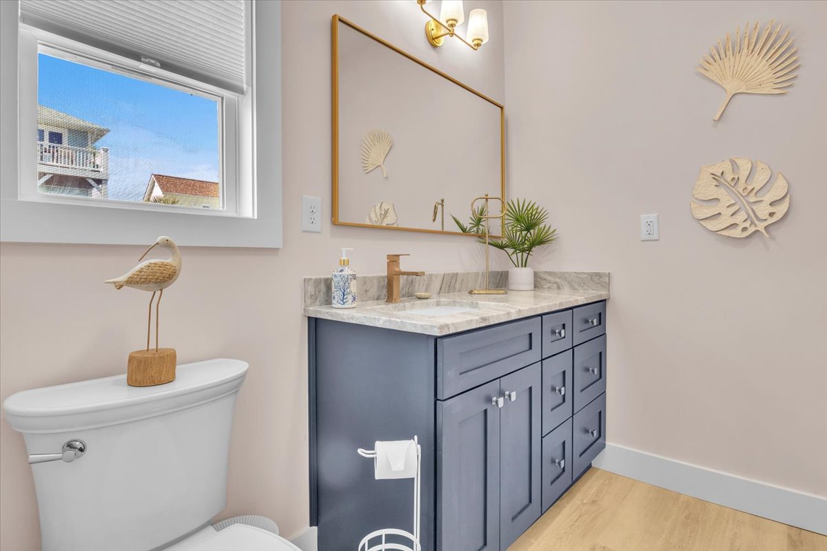 Refresh in your beautifully appointed bathroom featuring marble countertops, coastal decor, and natural light from the window.
