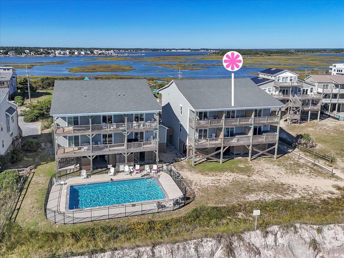 Aerial view of beachfront vacation rental complex with swimming pool, overlooking coastal marshlands and waterways.