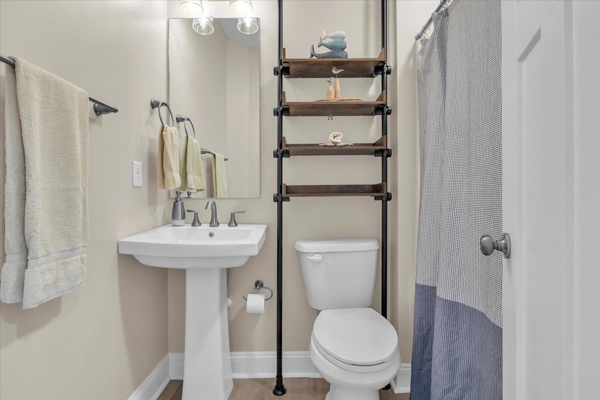 Your private bathroom features a pedestal sink, spacious shower, and thoughtful storage shelving to keep your essentials organized during your stay.