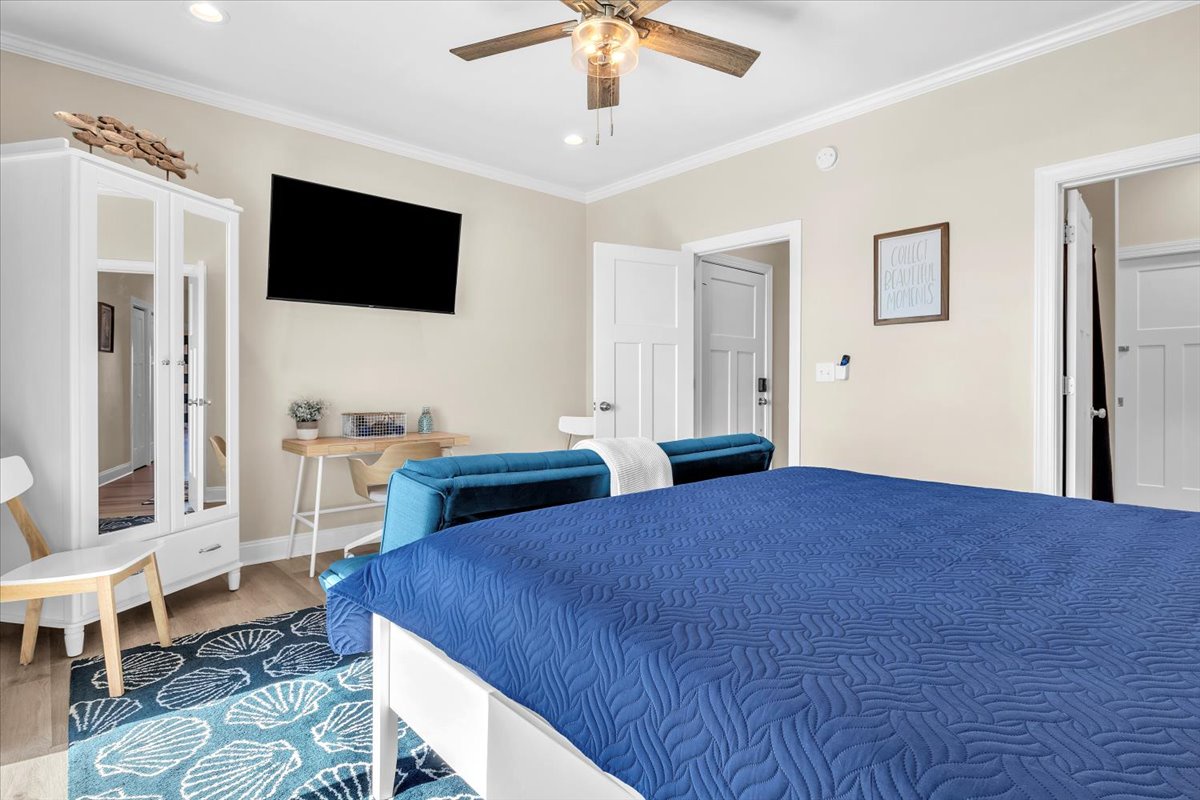 Your spacious bedroom offers comfort with a ceiling fan, wall-mounted TV, cozy seating area, and convenient workspace for ultimate relaxation.