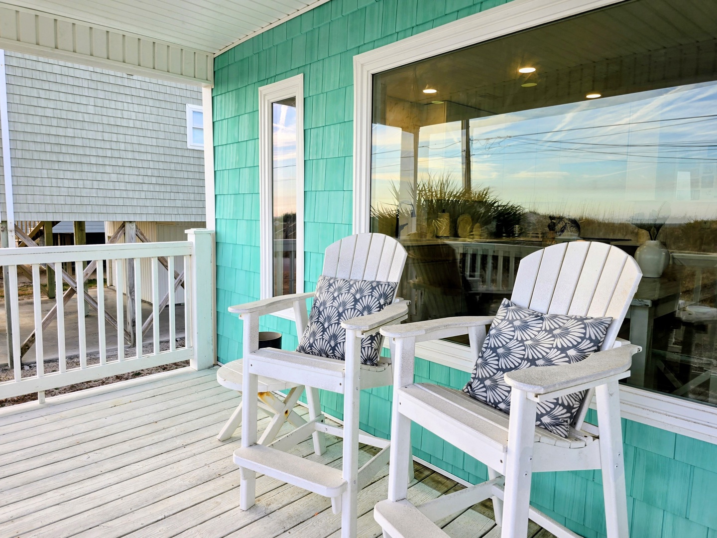 Relax on your private deck with coastal charm. Two white chairs with patterned cushions await your morning coffee or evening conversations.