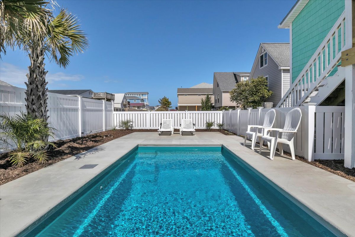 Your private pool paradise awaits, surrounded by tropical palms and sun loungers for the perfect coastal getaway.