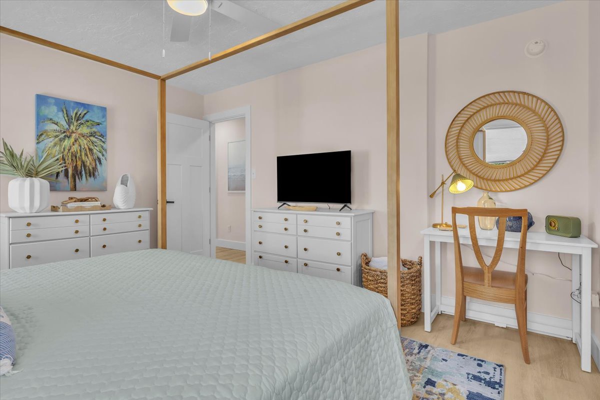 Relax in your serene coastal-inspired bedroom with soft linens, work desk, and tropical artwork creating the perfect retreat.