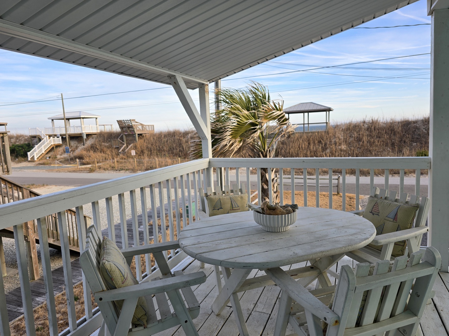 Your covered patio offers peaceful coastal dining with sea breezes, cushioned chairs, and serene beach views through native grasses.
