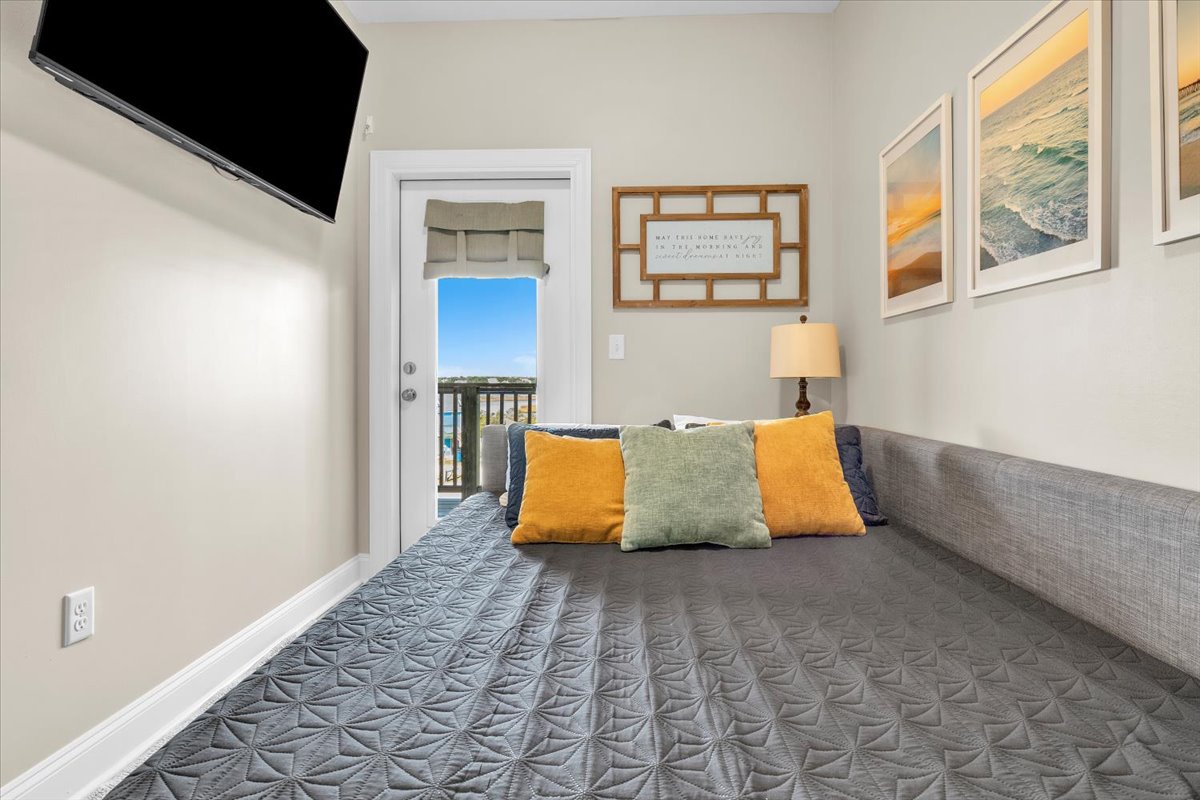 Relax in your cozy bedroom with vibrant pillows, peaceful coastal art, and your own private balcony access for morning coffee.