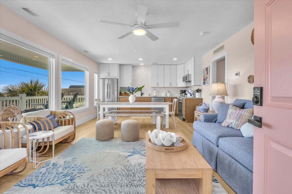Relax in your bright, coastal living space with comfy seating, open kitchen, and breezy ceiling fan overhead.