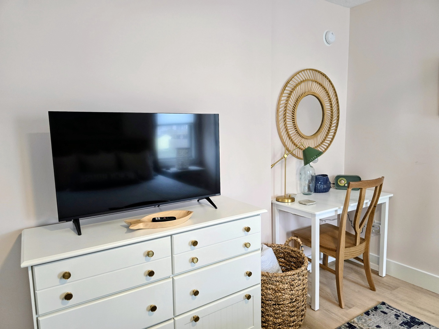 Your stylish bedroom corner features a large flat-screen TV, cozy workspace with natural lighting, and thoughtful storage solutions for a comfortable stay.