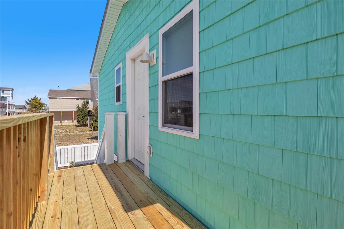 Bright turquoise siding creates a cheerful coastal vibe on this charming property exterior with welcoming entrance.