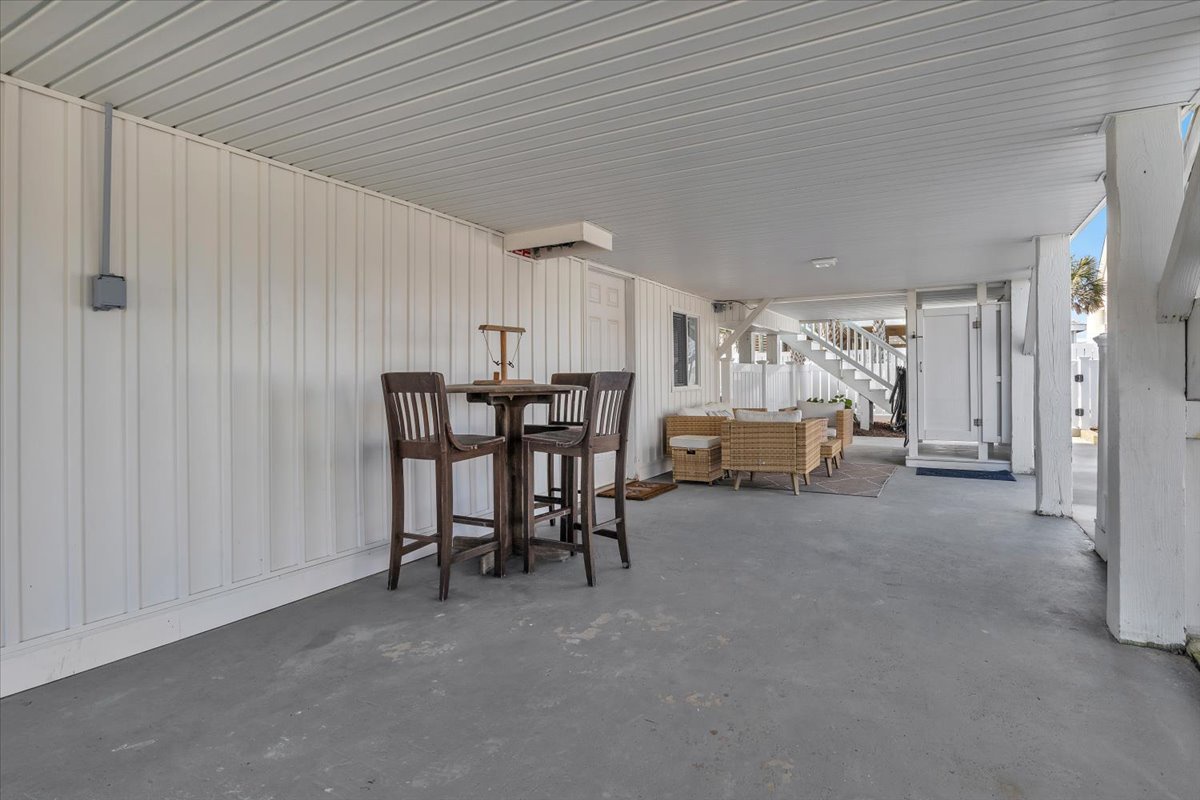 Your covered patio offers comfortable outdoor dining and lounging spaces with concrete flooring and coastal charm.