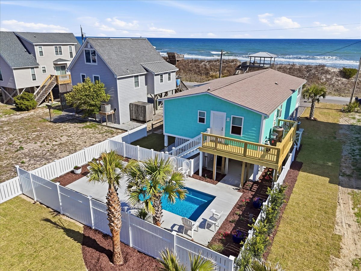 Charming beachfront property features a private pool and direct ocean access, surrounded by coastal homes in a peaceful seaside community.