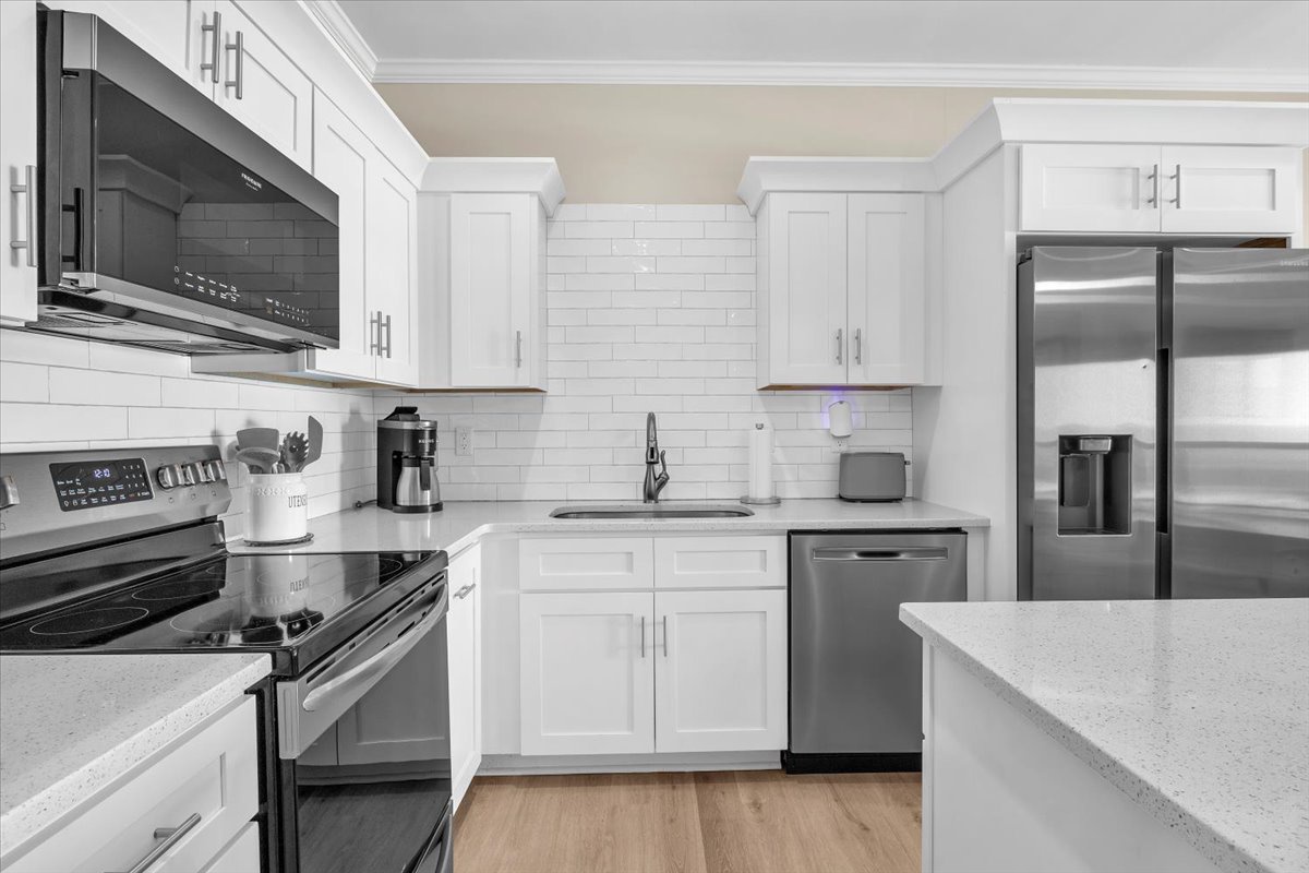 Your fully equipped kitchen features modern stainless steel appliances, pristine white cabinetry, and sleek quartz countertops—perfect for preparing meals during your stay.