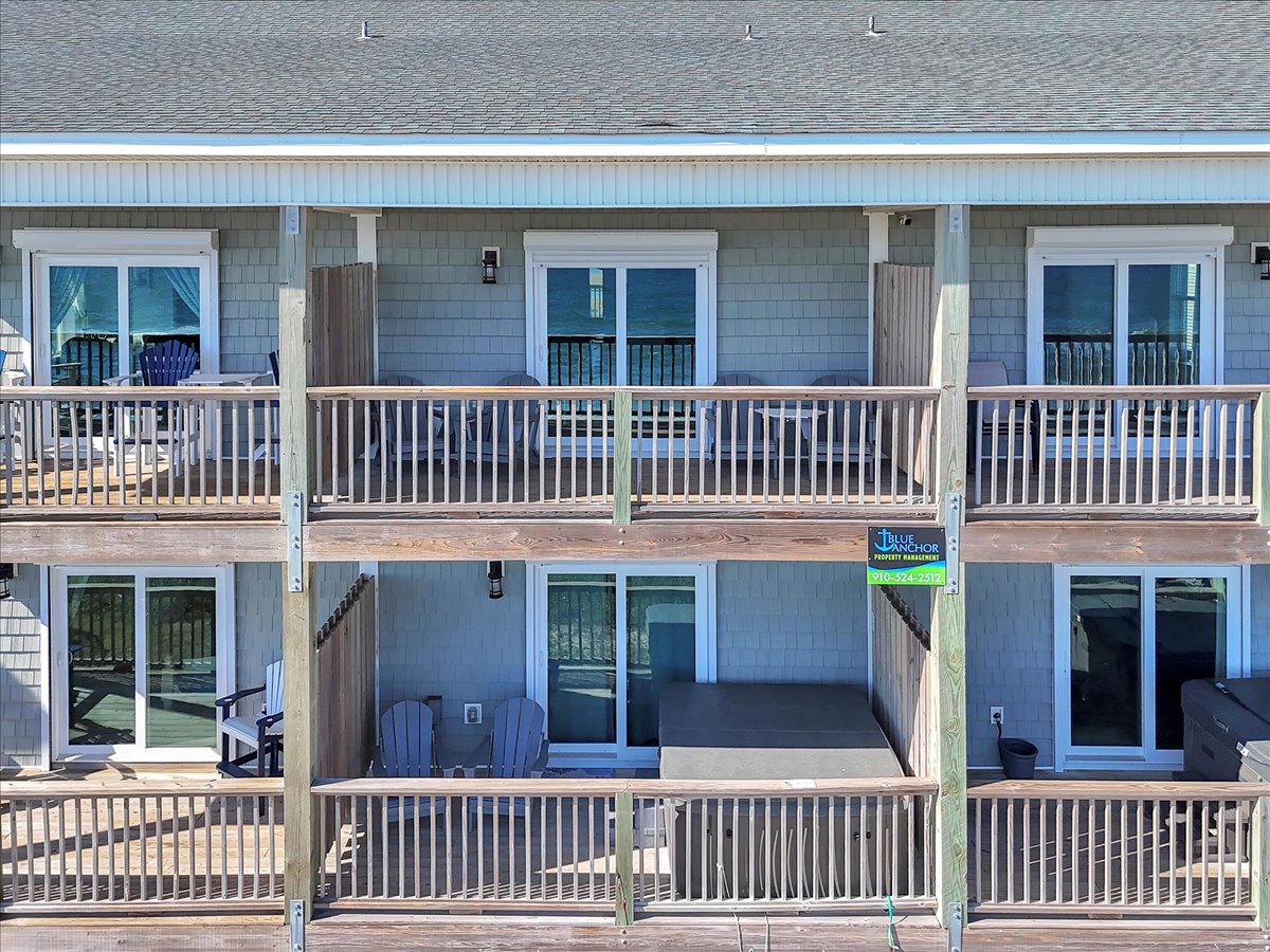 Coastal property building featuring multiple units with private balconies and outdoor seating areas, offering convenient beachside accommodation.