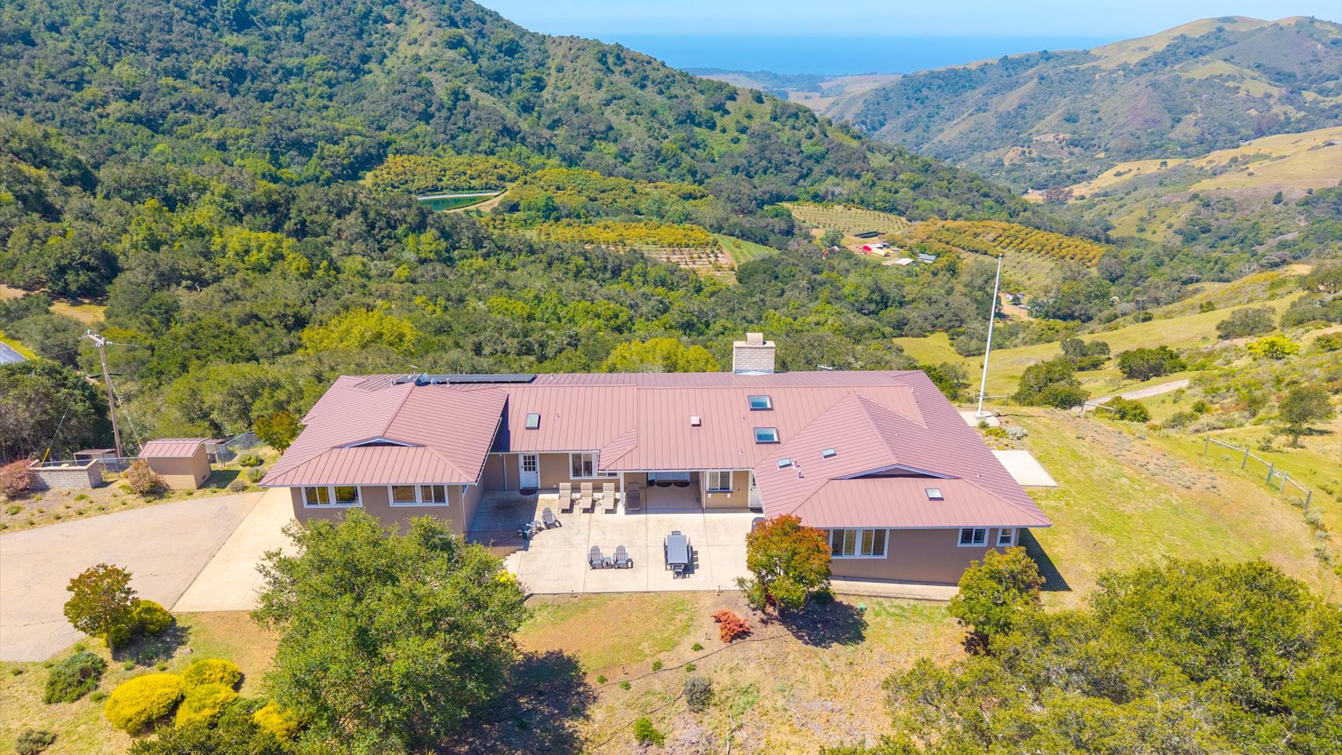 The home offers multiple patios and outdoor spaces, with sweeping views in all directions and views of the ocean in the distance