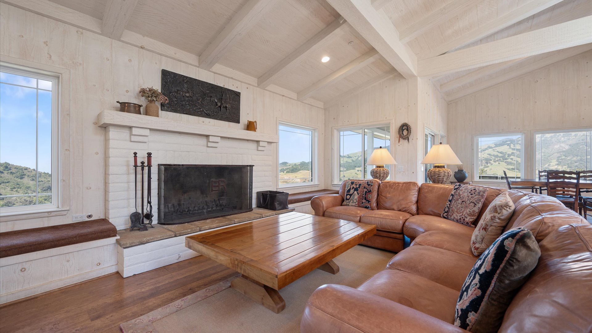 Unwind on plush leather sofas before a crackling fireplace, surrounded by vaulted ceilings and panoramic windows framing stunning vistas.