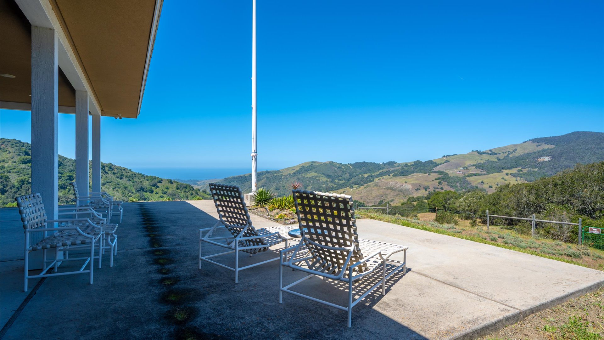 Expansive hilltop terrace with panoramic mountain and distant ocean views.