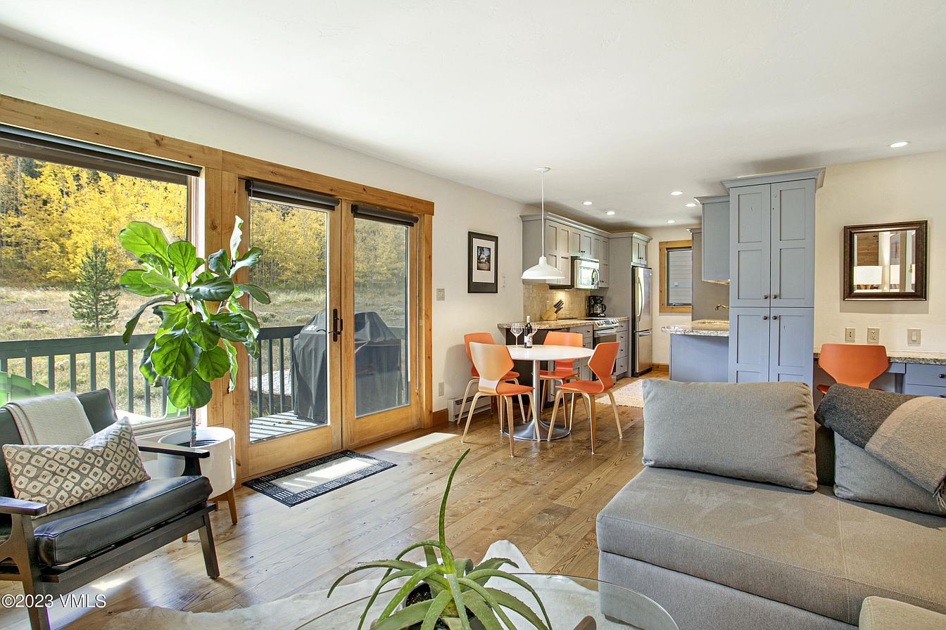 Step into your open-concept retreat where natural light floods the living, dining, and kitchen areas. Relax on the cozy sofa, enjoy meals at the cheerful table, and take in autumn views through the glass doors.