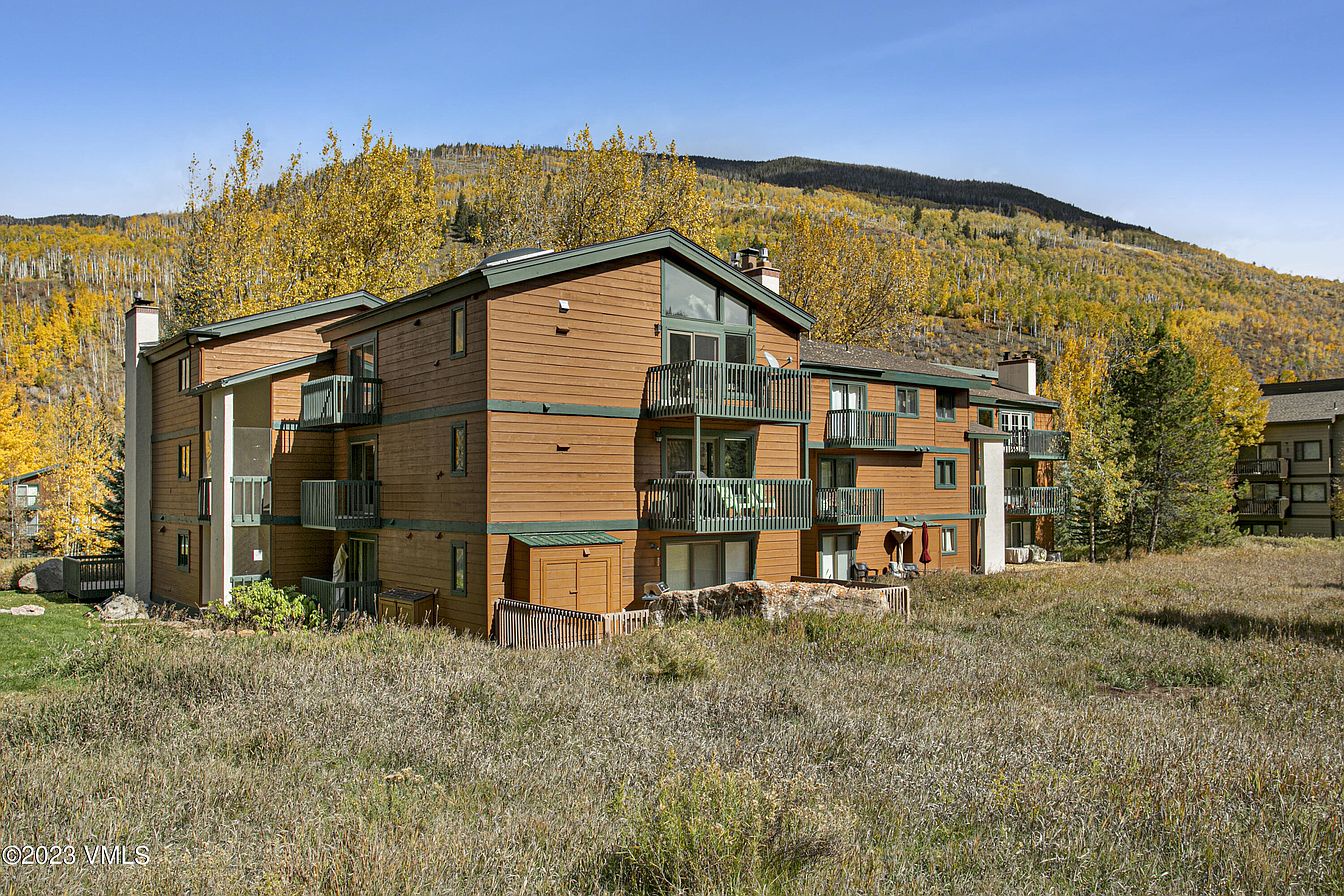 Multi-level mountain property with balconies set against vibrant autumn aspens and forested hillsides, offering access to seasonal outdoor recreation and scenic surroundings.