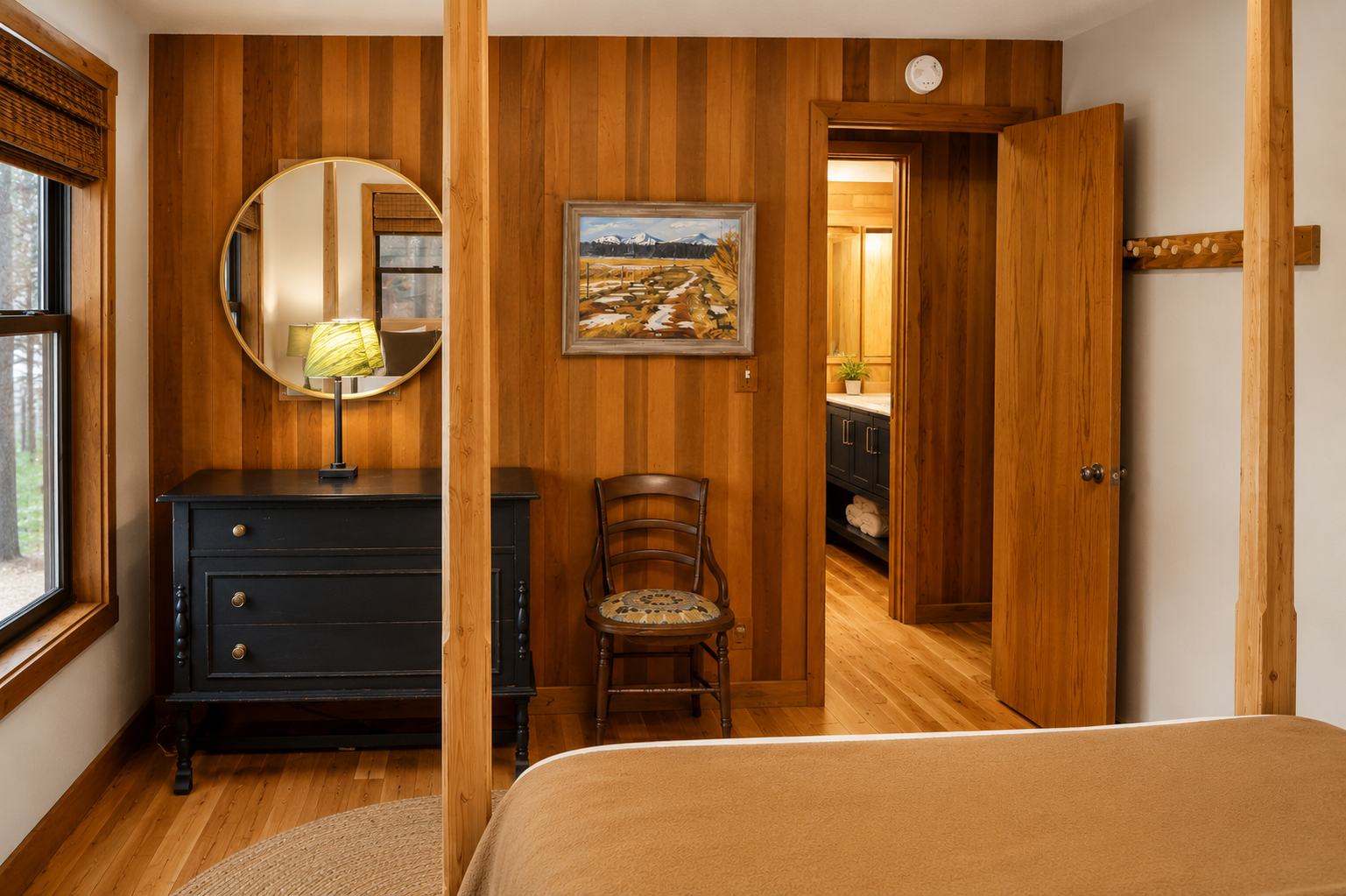 Your cozy bedroom features warm wood paneling, vintage furnishings, and a charming dresser with a round mirror—perfect for unwinding after a day of adventure.