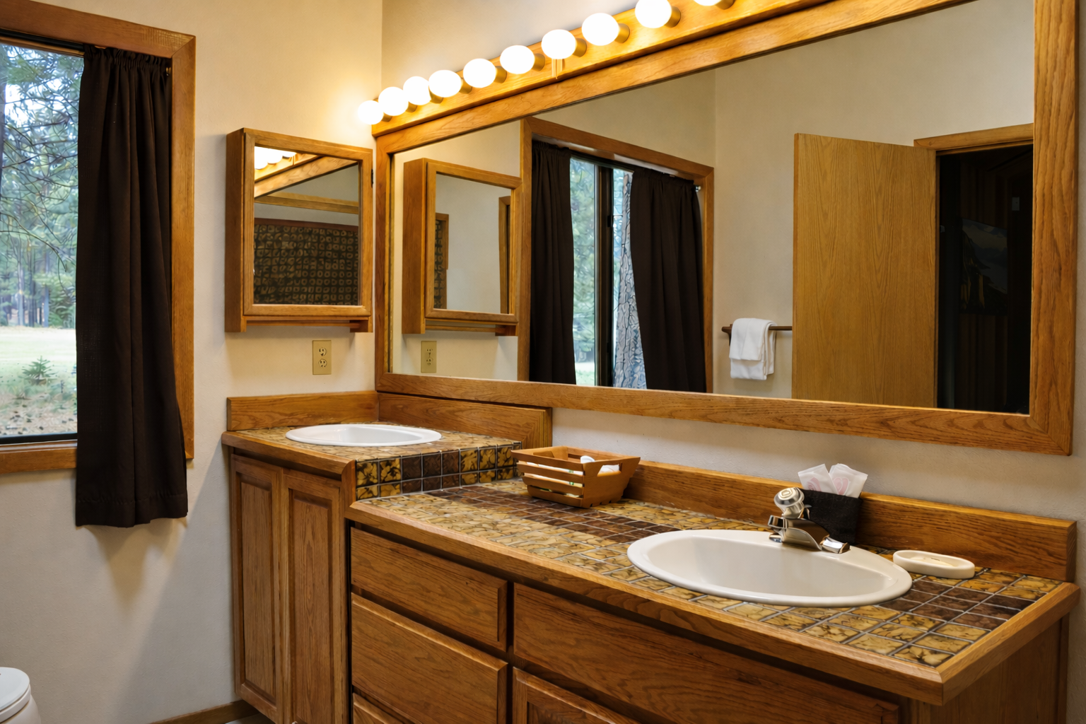 Enjoy the spacious dual-sink vanity with warm wood finishes and Hollywood-style lighting for your morning routines.