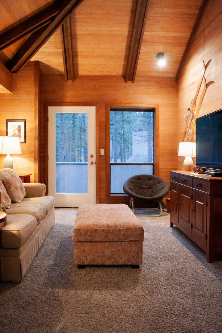 Unwind in your cozy cabin-style living room with exposed beams, plush seating, and peaceful forest views