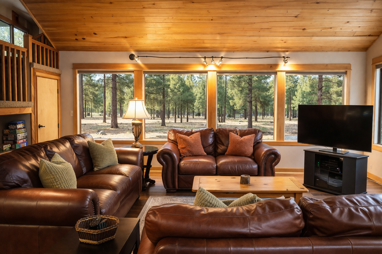 Sink into luxurious leather seating while enjoying forest views through expansive windows in this warm, rustic living space.
