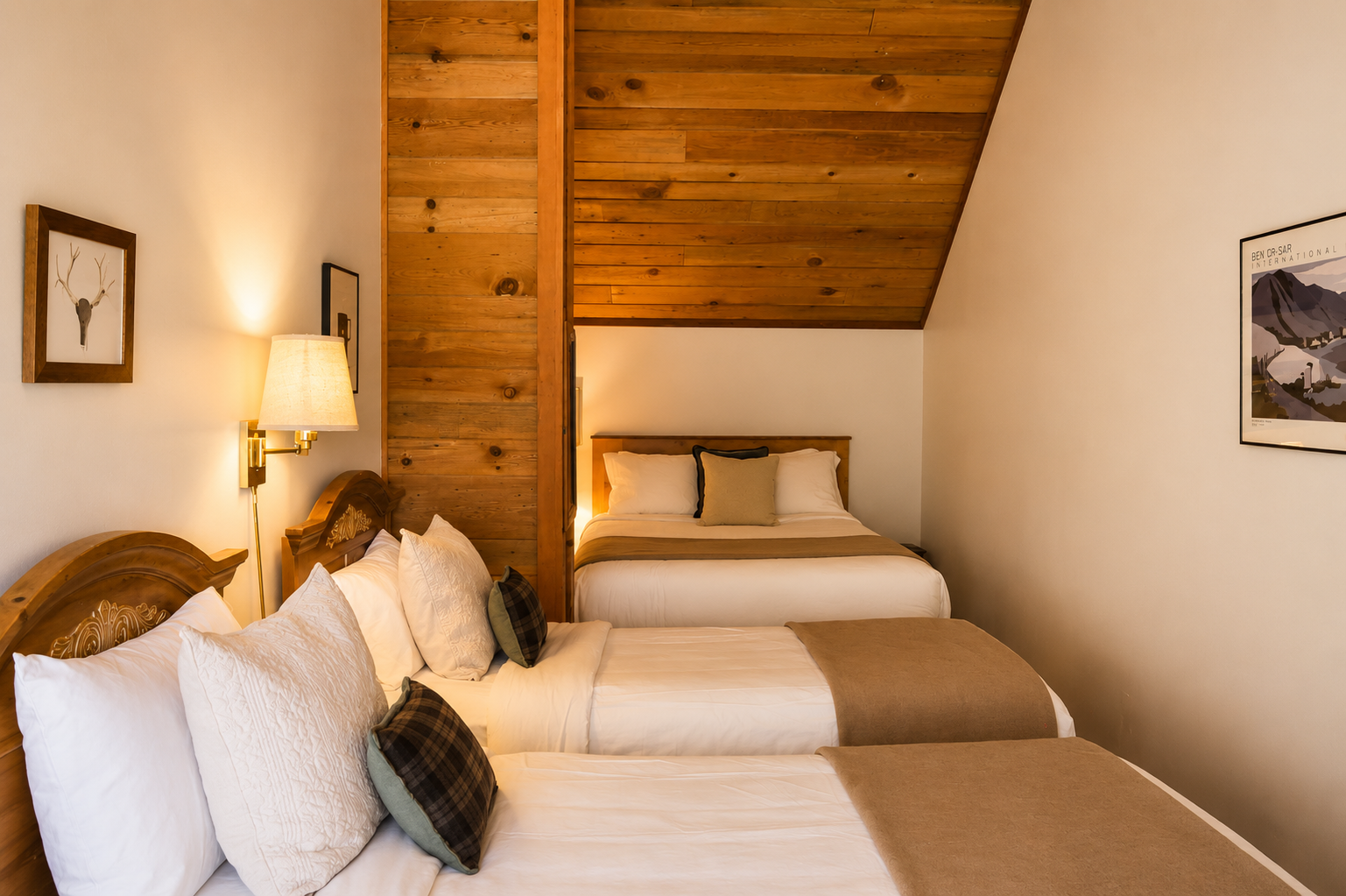 Your cozy mountain retreat features warm wood-beam ceilings and two plush beds dressed in crisp linens. Soft bedside lighting adds a welcoming glow, inviting you to unwind in rustic comfort.