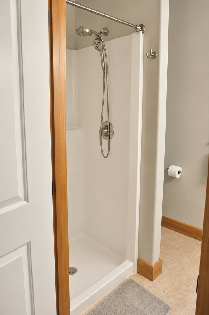 Step into your private walk-in shower with modern dual showerheads—a refreshing escape after a day of adventure, with clean white walls and warm wood accents.