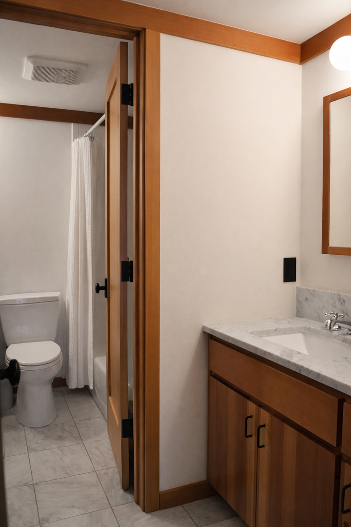 Your private bathroom features warm wood accents, marble countertops, and a separate shower area for comfortable morning routines.