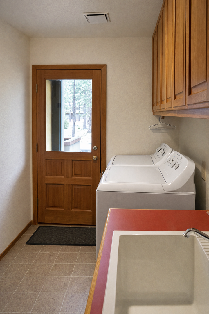 Your private laundry room features full-size washer and dryer with wooden cabinetry for convenient storage during your stay.