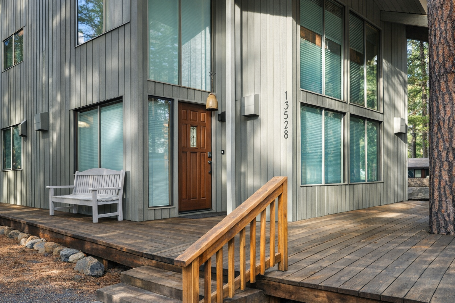 Modern vacation home featuring natural wood siding and a welcoming covered deck with forest surroundings.