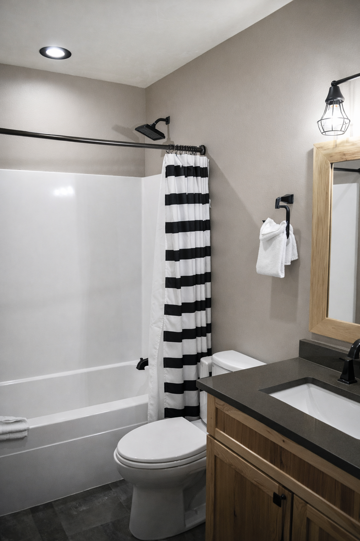 Refresh in your private bathroom featuring a full tub-shower combo, stylish striped curtain, and modern vanity with ample counter space.