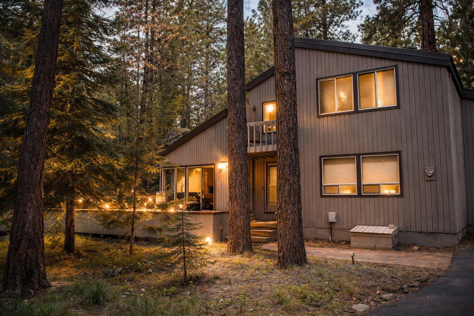 Modern forest cabin nestled among towering pines, warm lights glowing through windows as evening falls across this peaceful wooded retreat.